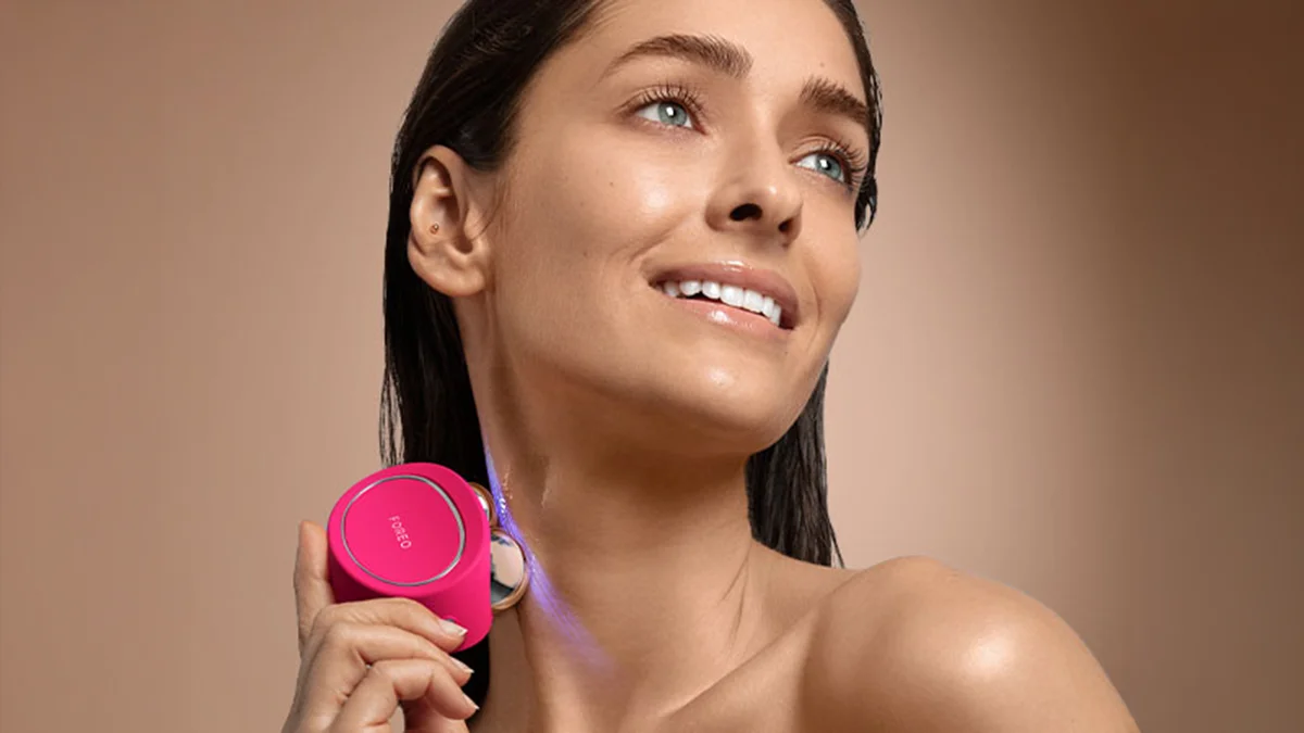 A woman demonstrating microcurrent therapy device movement on teh side of the neck